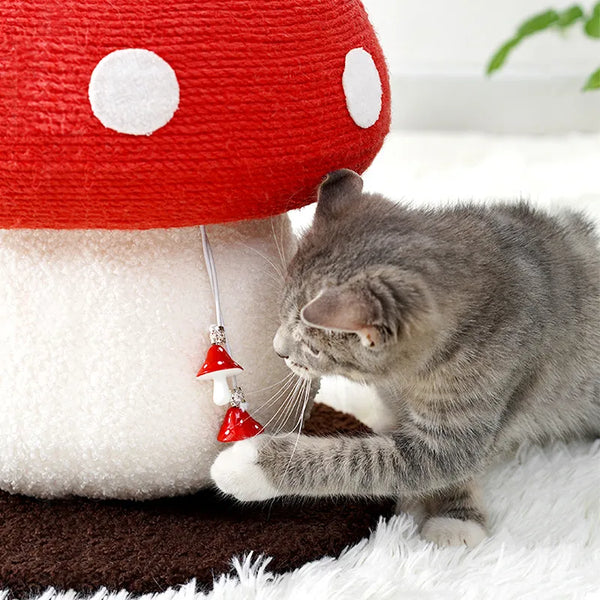 Cat playing with a mushroom-shaped toy on a soft surface