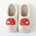 Pair of white slippers with red mushroom design on a white background