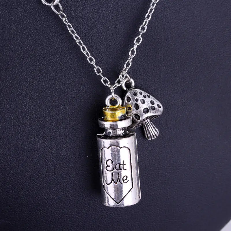 Silver necklace with a bottle charm and 'Eat Me' inscription on a dark background