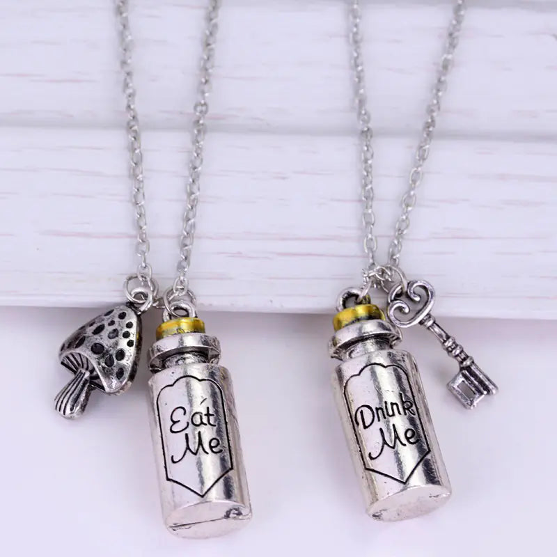 Two silver necklaces with 'Eat Me' and 'Drink Me' bottle pendants on a white background.