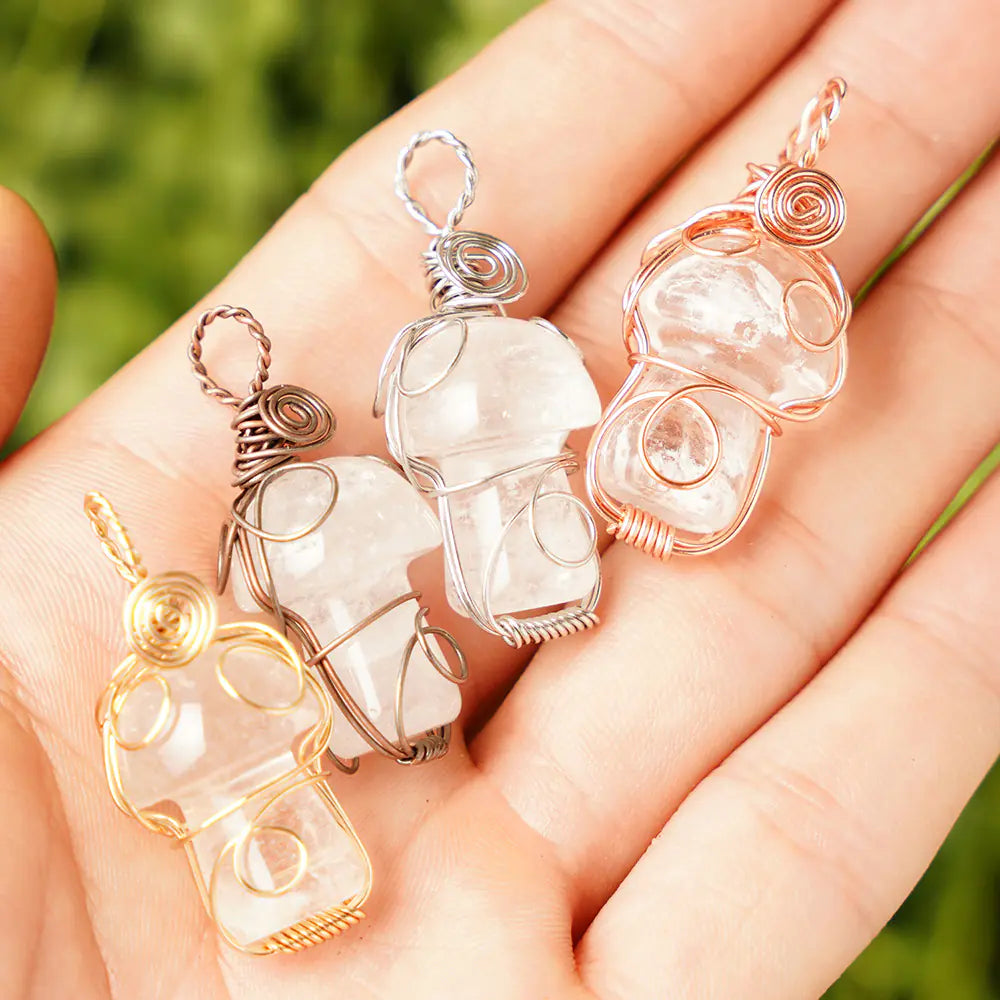 Four crystal pendants in gold, silver, and rose gold on a hand with a blurred green background