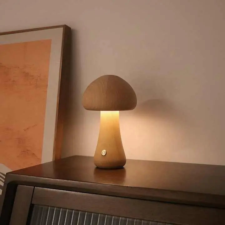 Wooden mushroom-shaped lamp on a surface with a warm glow, next to a framed picture.