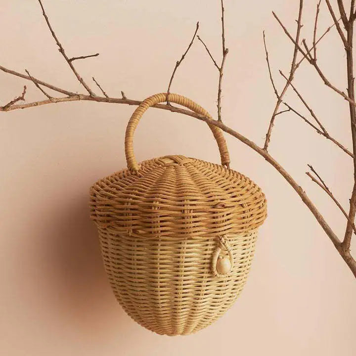 Wicker basket with handle hanging on a branch against a beige background