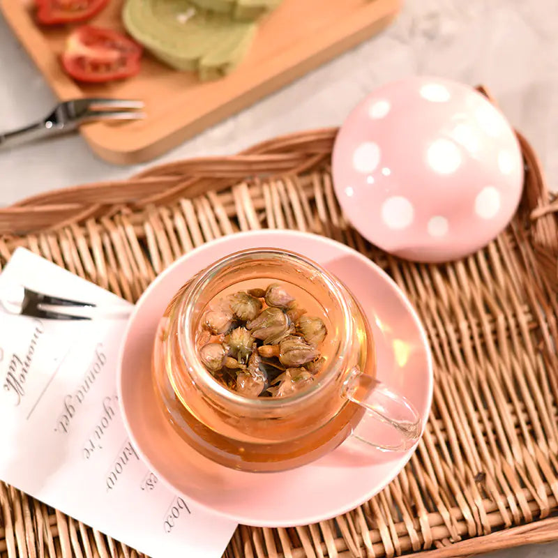 Tea cup with tea leaves on a pink saucer on a woven mat