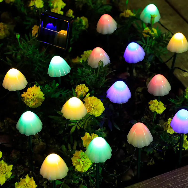 Colorful mushroom-shaped garden lights on a grassy area with flowers.
