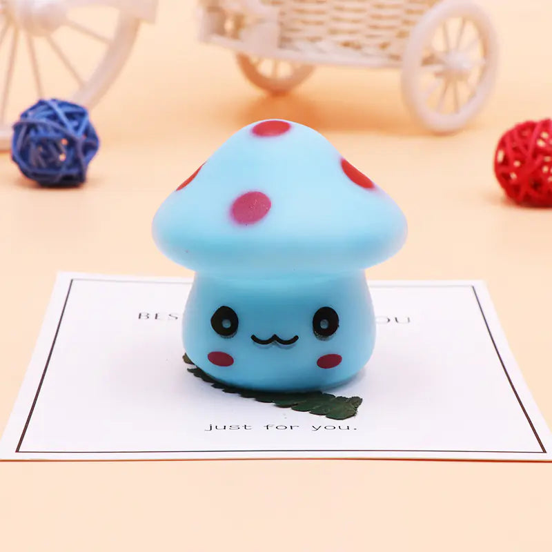 Blue mushroom-shaped squishy toy with red spots on a light surface