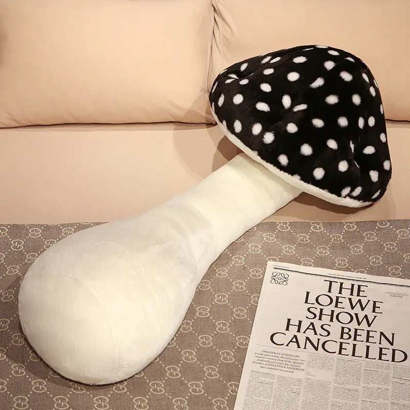 Black and white polka dot mushroom-shaped pillow on a surface with a newspaper.