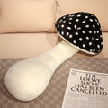 Black and white polka dot mushroom-shaped pillow on a surface with a newspaper.