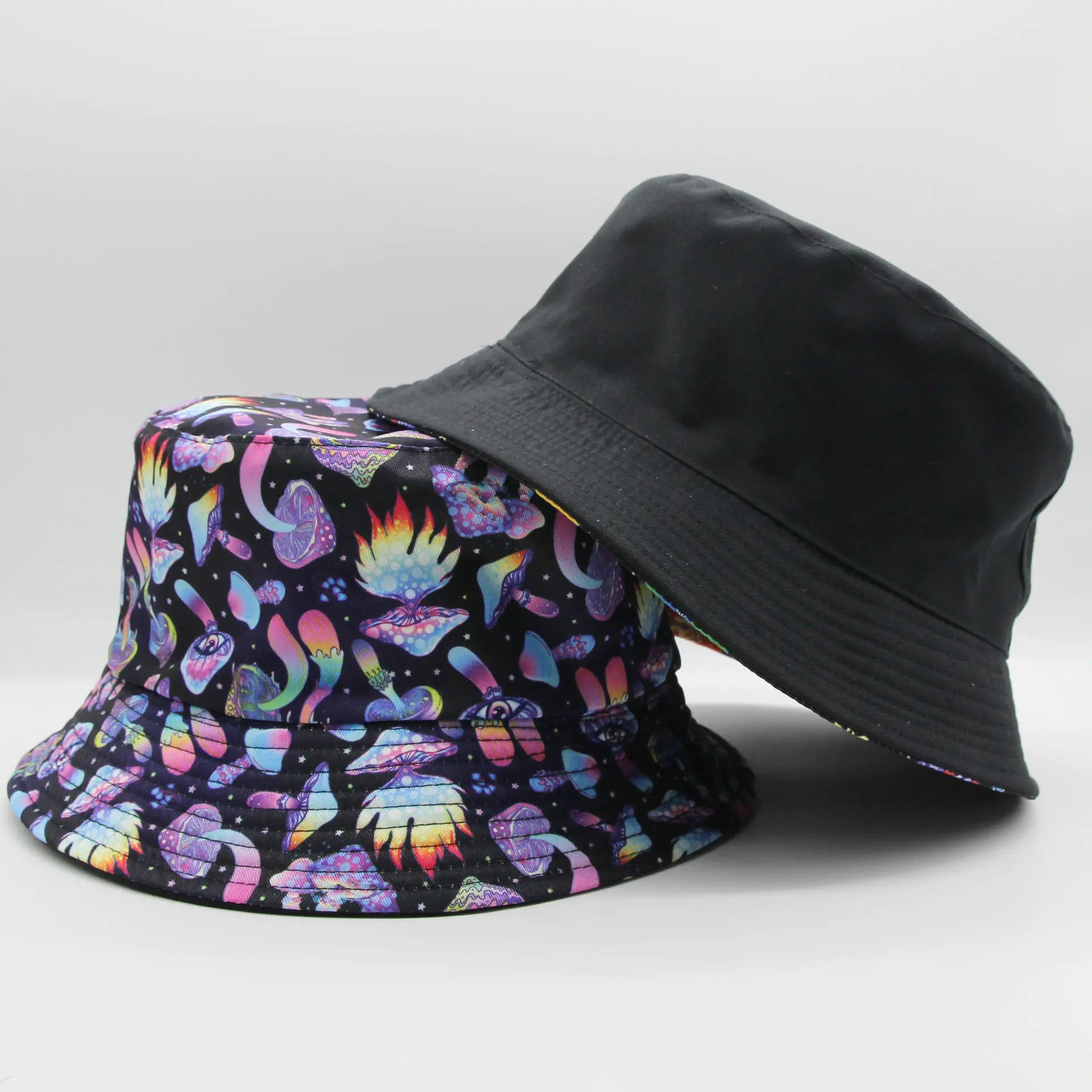Two bucket hats, one with a colorful butterfly pattern and the other black, on a light gray background.