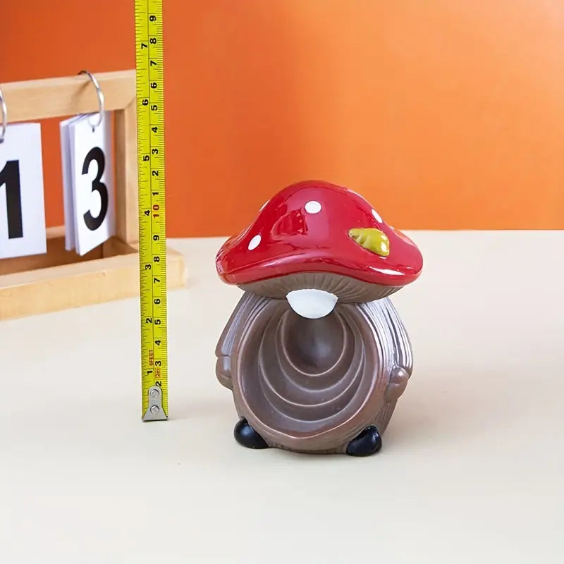 Mushroom-shaped object with a red cap and brown stem on a white surface, with a measuring tape for scale.