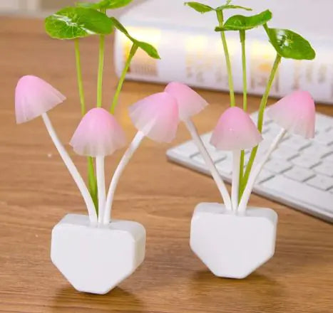 Two pink mushroom-shaped lights in white hexagonal pots on a wooden surface with a keyboard in the background.