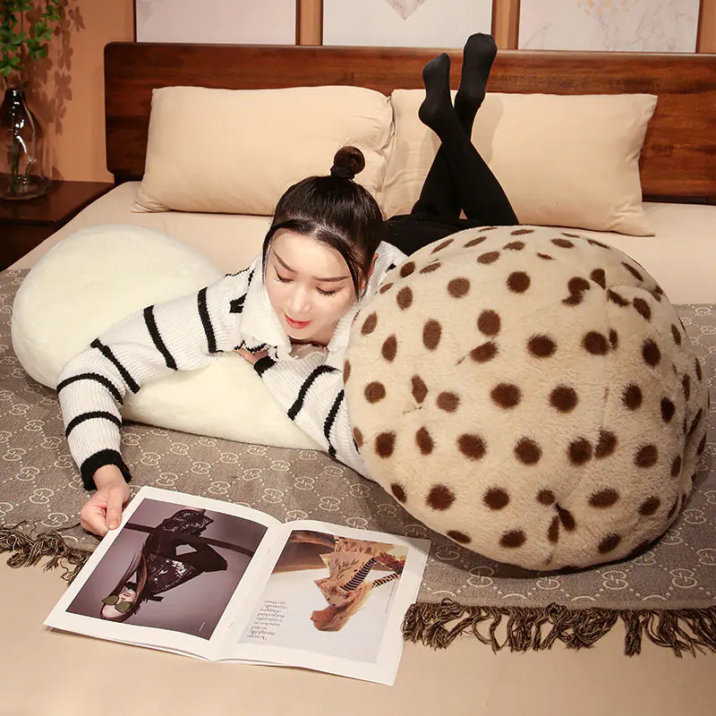 Woman lying on a bed with polka dot cushions reading a magazine