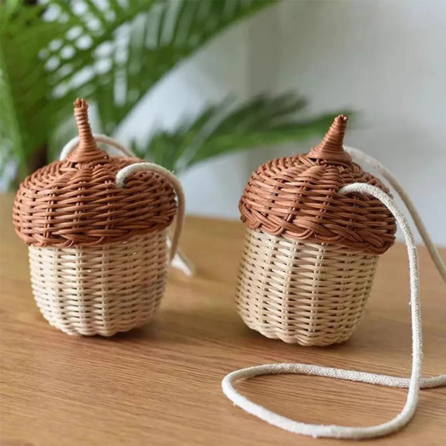 Two woven acorn-shaped bags with a cord on a wooden surface.