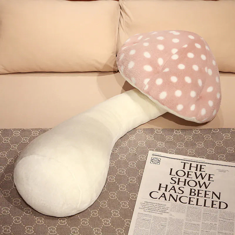 White and pink mushroom-shaped pillow on a patterned surface with a newspaper.
