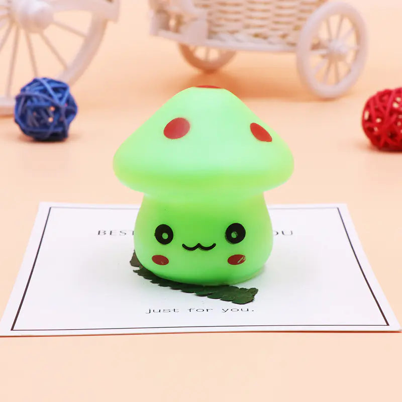 Green mushroom-shaped squishy toy on a beige surface with decorative elements.
