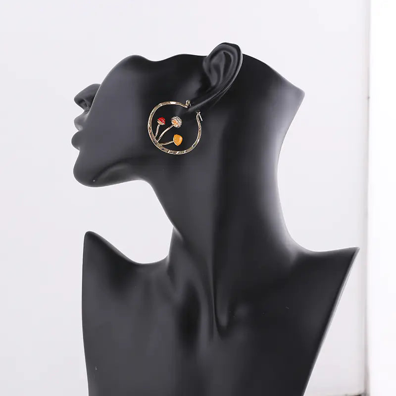 Gold hoop earring with colorful stones on a black mannequin bust against a white background