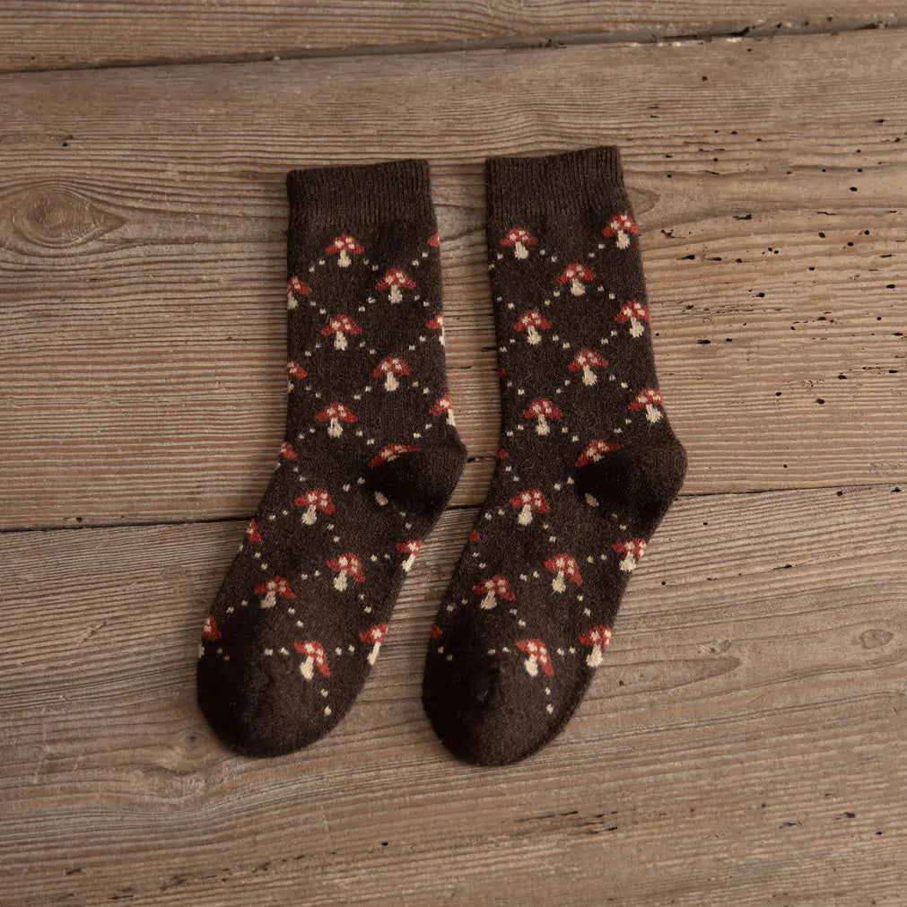 Pair of brown socks with mushroom pattern on a wooden surface