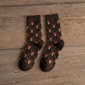 Pair of brown socks with mushroom pattern on a wooden surface