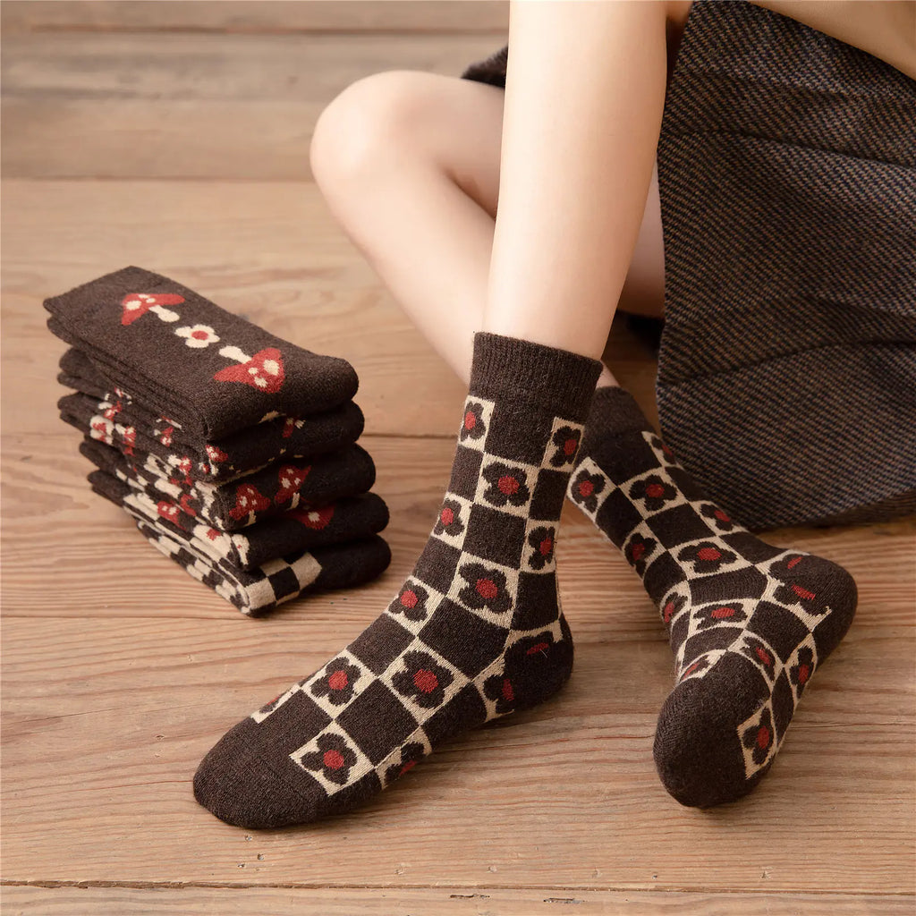 Stack of patterned socks on a wooden floor with a person wearing one sock.