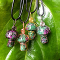 Four colorful mushroom-shaped pendants on black cords against a green leaf background