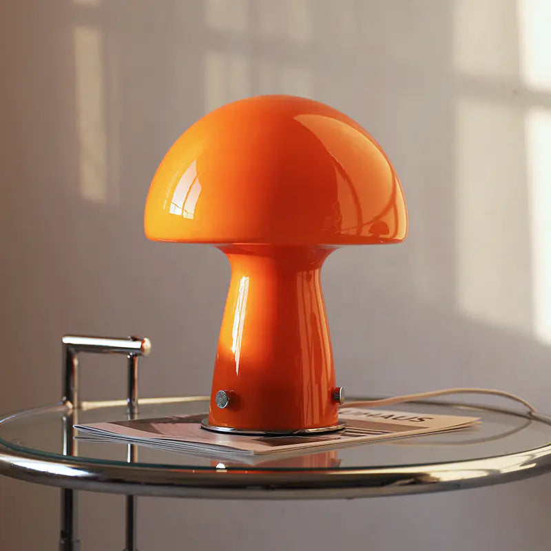 Orange mushroom lamp on a glass table with a neutral background