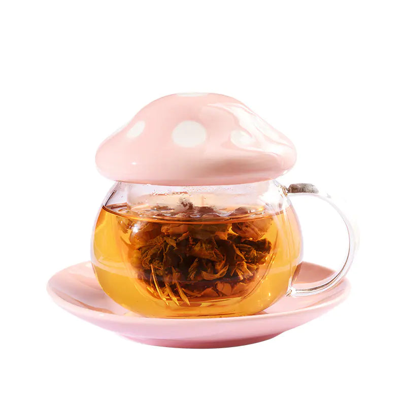 Mushroom-shaped glass teapot with pink lid and base, filled with tea, on a white background.