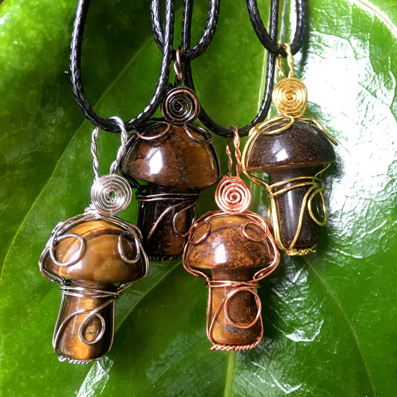 Three mushroom-shaped pendants on black cords against a green leaf background