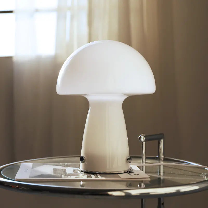 White mushroom-shaped lamp on a glass table with a blurred background