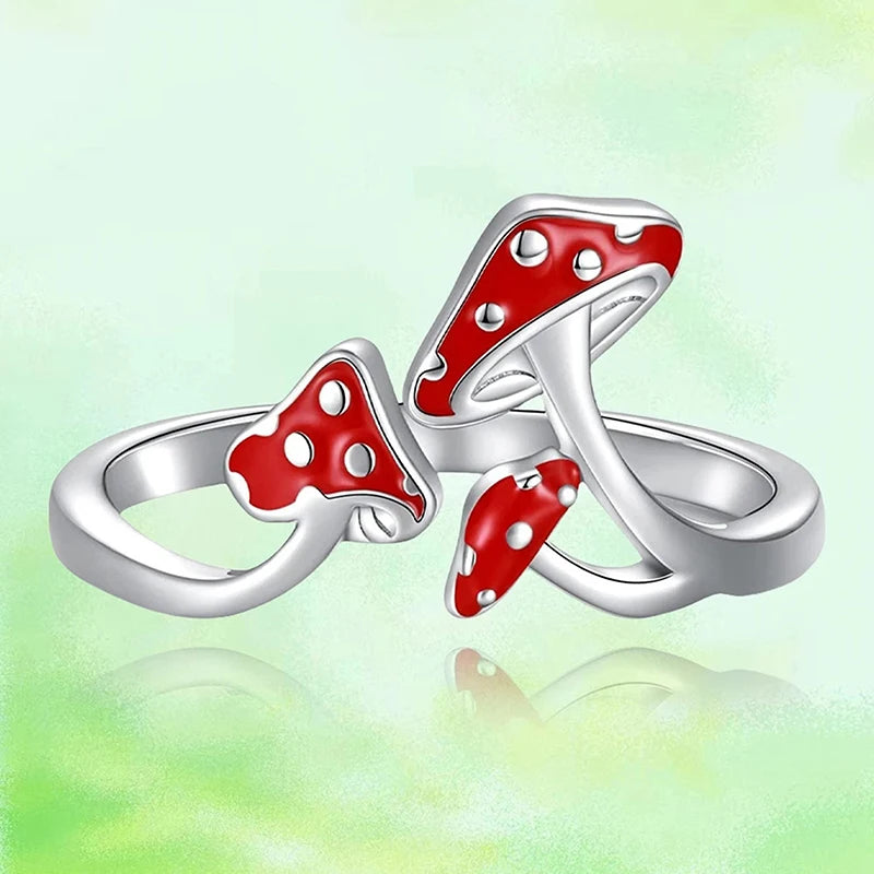 Silver rings with red mushroom design on a light green background