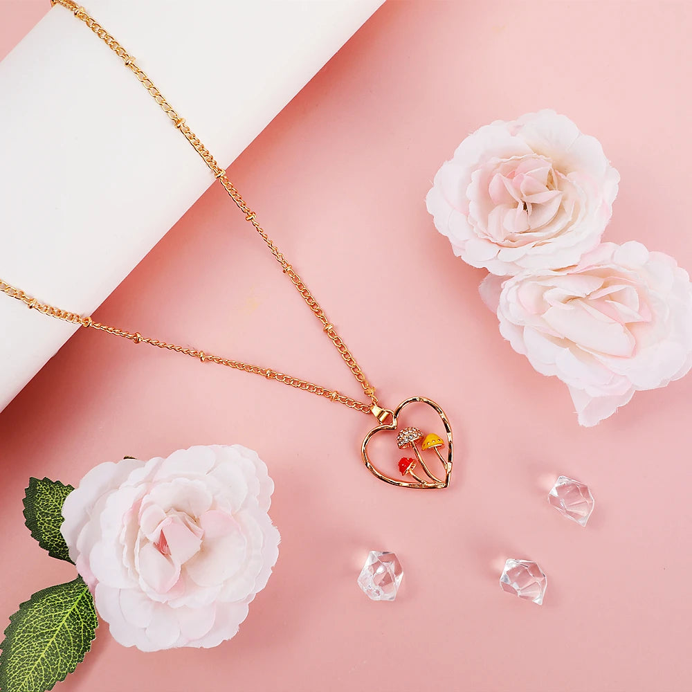 Gold necklace with a heart-shaped pendant on a pink background with flowers and crystals.