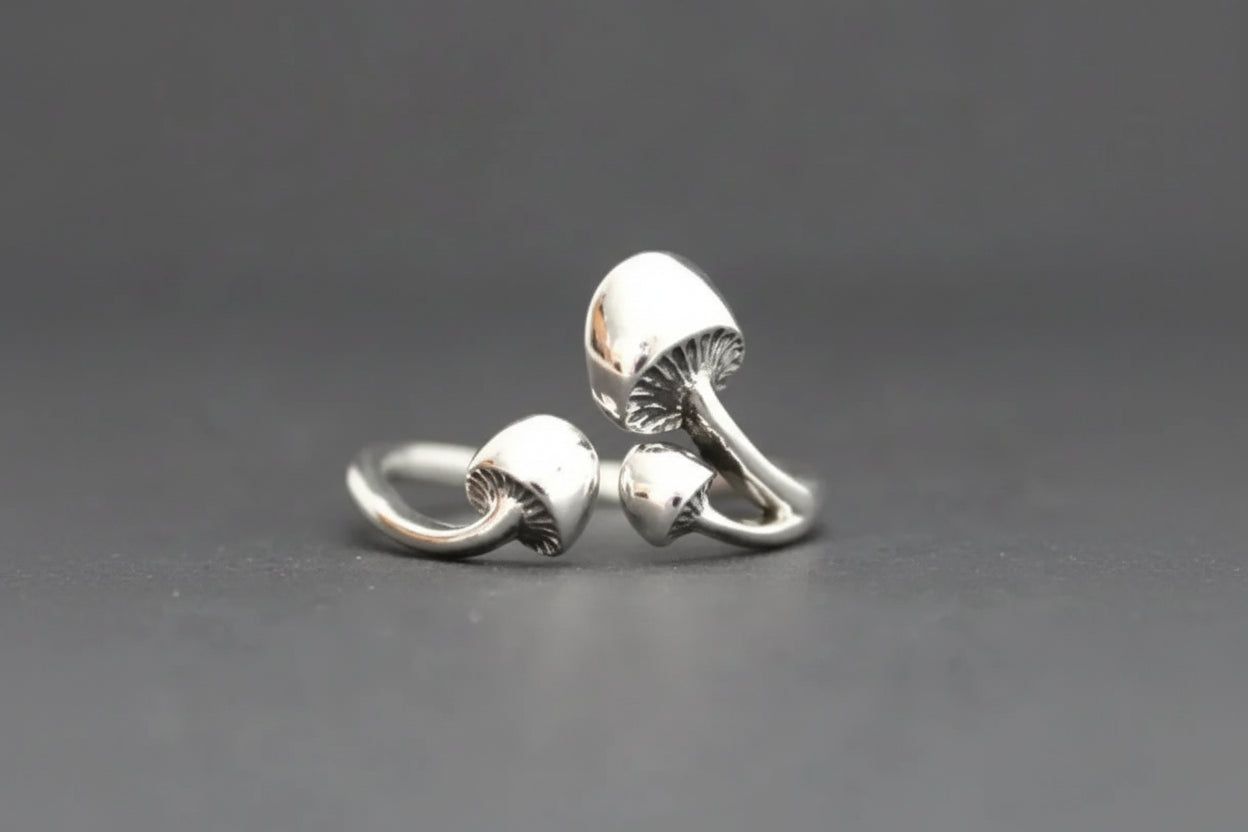 Silver mushroom-shaped earrings on a gray background