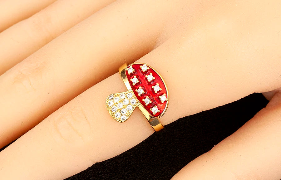 Gold ring with red gemstone and white stones on a finger