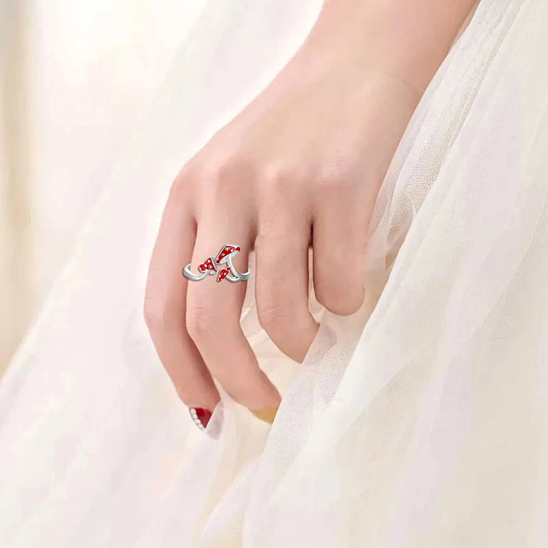 Silver ring with red gemstones on a hand against a white background