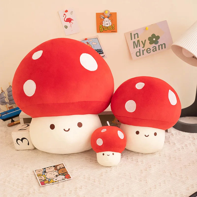 Set of red and white mushroom-shaped plush toys on a bed with decorative cards in the background.