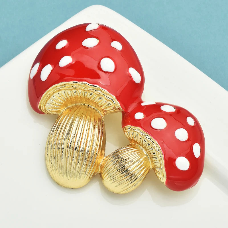 Red mushroom-shaped earrings with gold stems on a white platform.