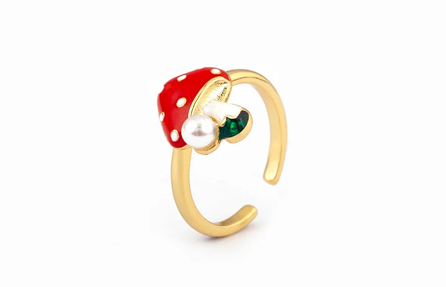 Gold ring with a red polka dot gemstone and pearl on a white background