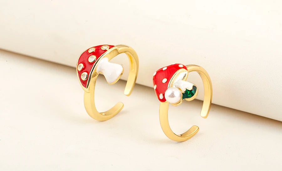Gold earrings with red and white polka dot design on a beige background