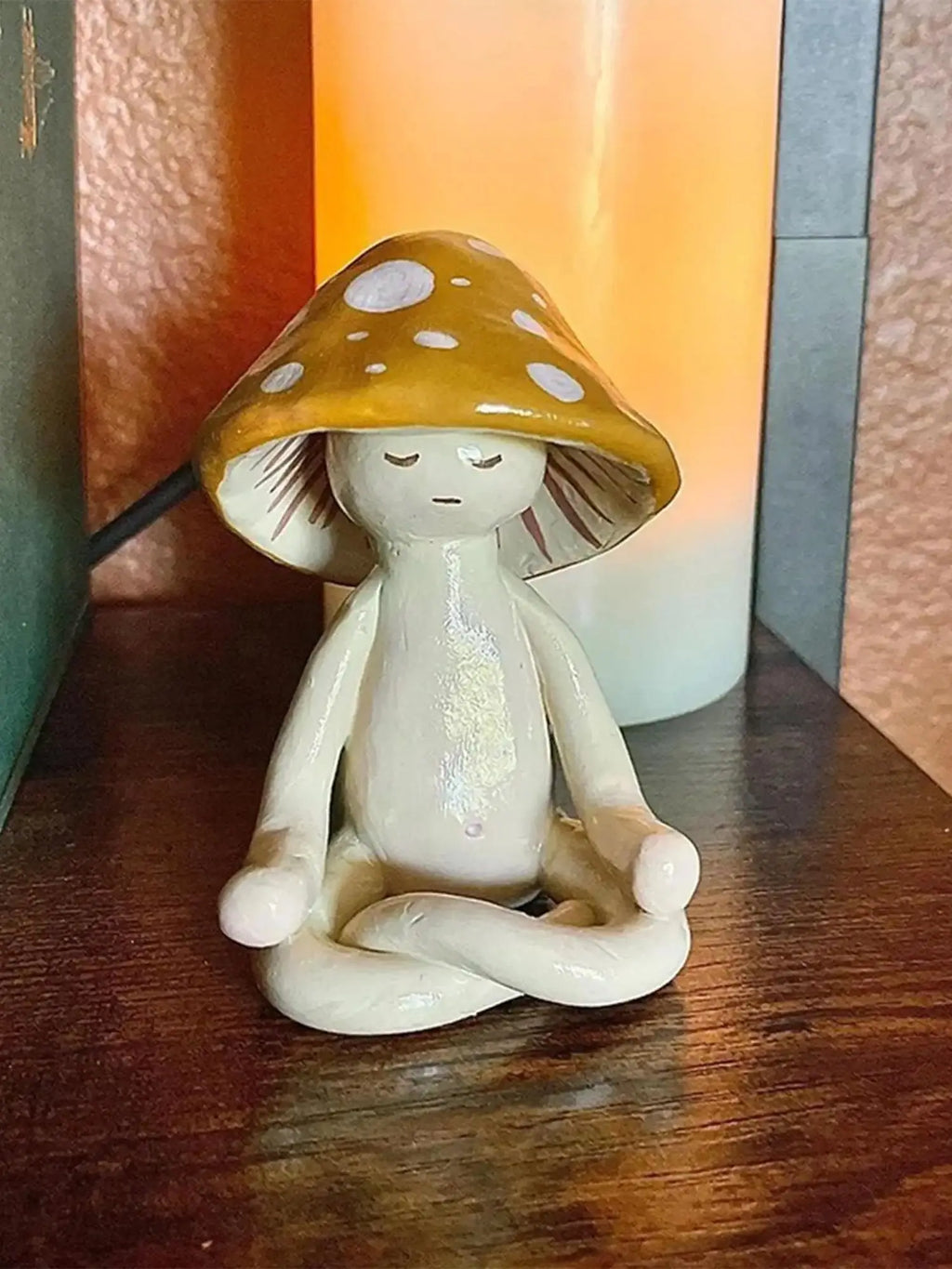 Ceramic figurine of a mushroom with a polka dot cap on a wooden surface.