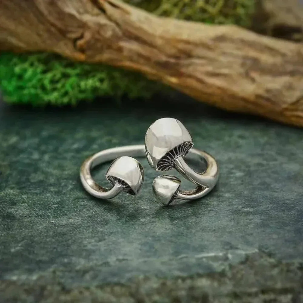 Silver mushroom-shaped ring on a textured stone surface with natural background