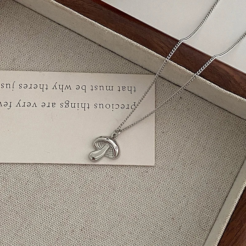 Silver necklace with a pendant on a card with text, placed on a textured surface.