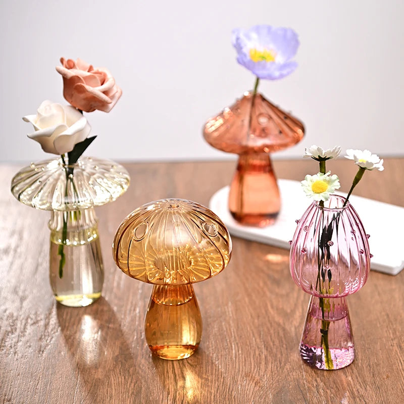 Set of colorful glass vases with flowers on a wooden surface