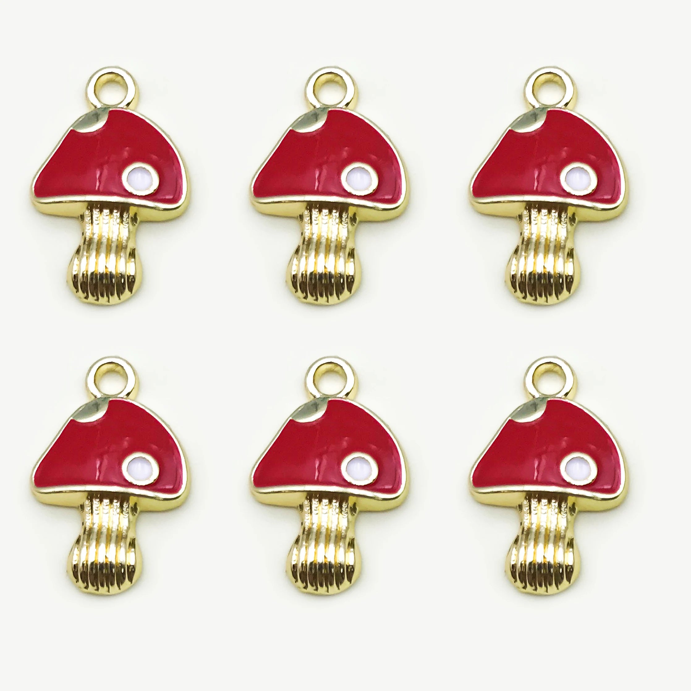 Six red mushroom-shaped charms with gold bases on a white background