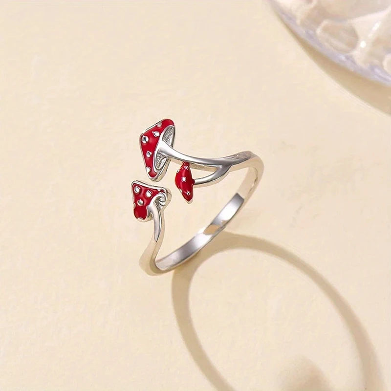 Silver ring with red mushroom-shaped stones on a beige background