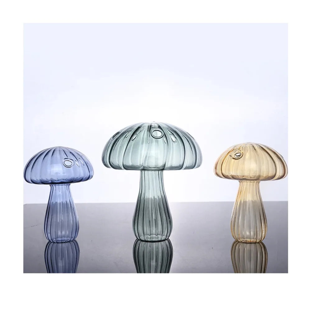 Three colorful glass mushroom-shaped lamps on a reflective surface with a light blue background