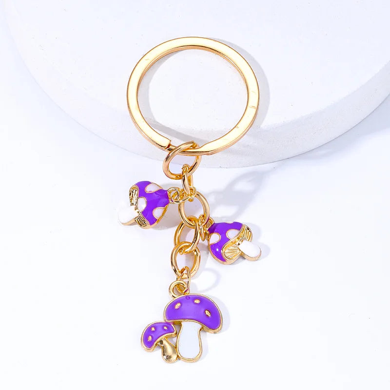 Gold keychain with purple mushroom charms on a white background