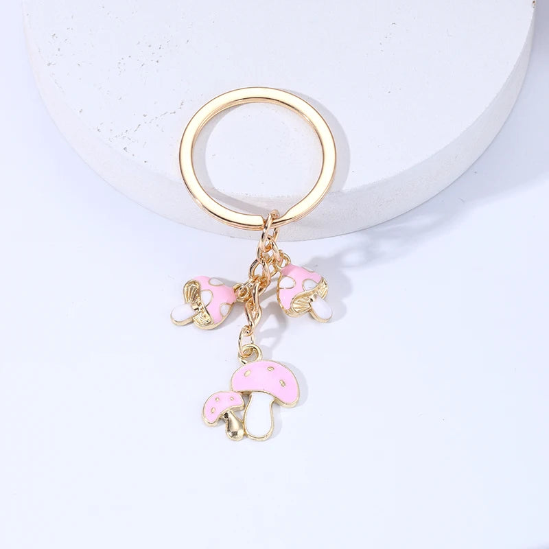 Gold keychain with pink mushroom charms on a light gray background