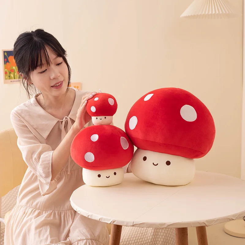 Woman holding red mushroom-shaped plush toys in a room with a lamp and wall art.