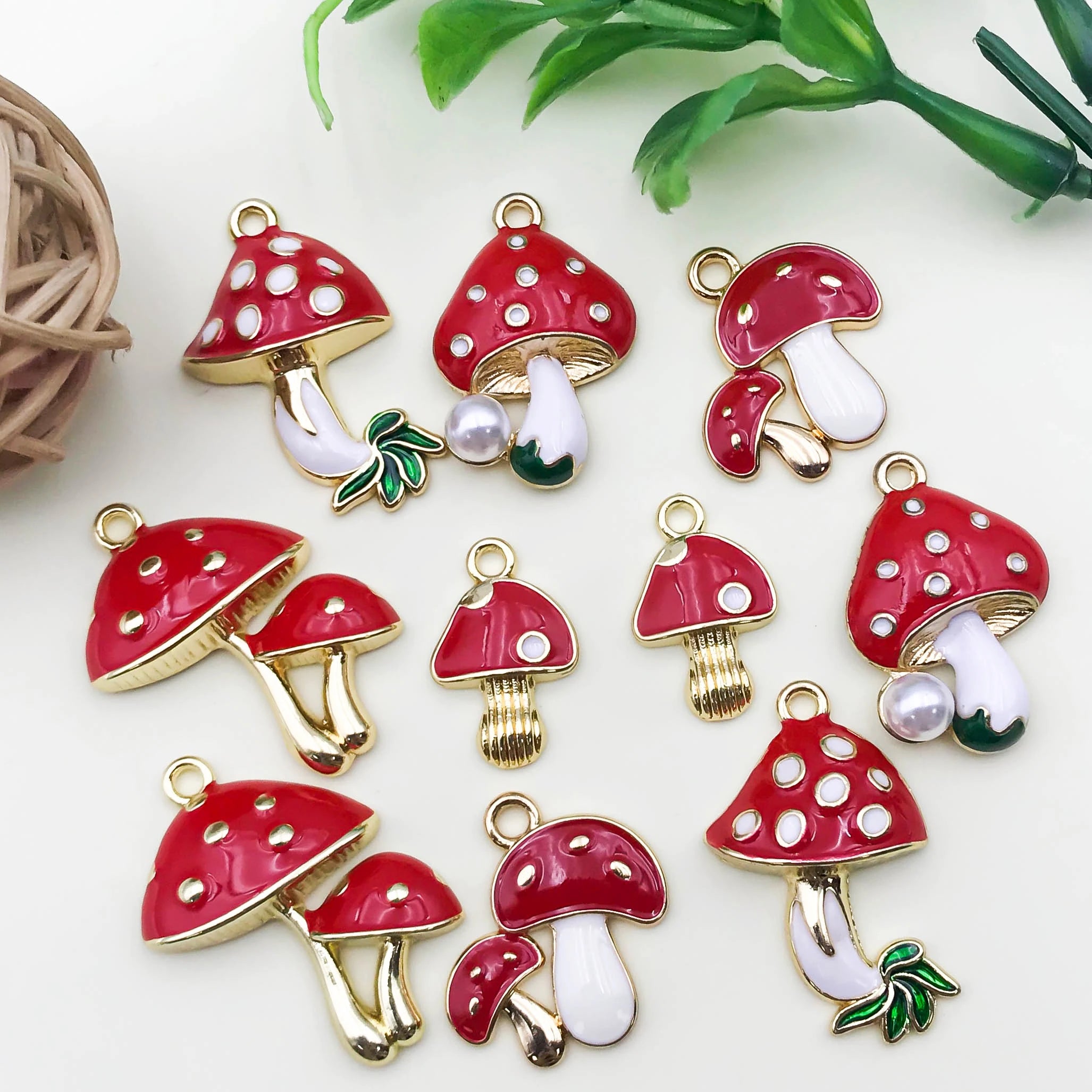 Red and gold mushroom-shaped charms on a white background with green leaves.