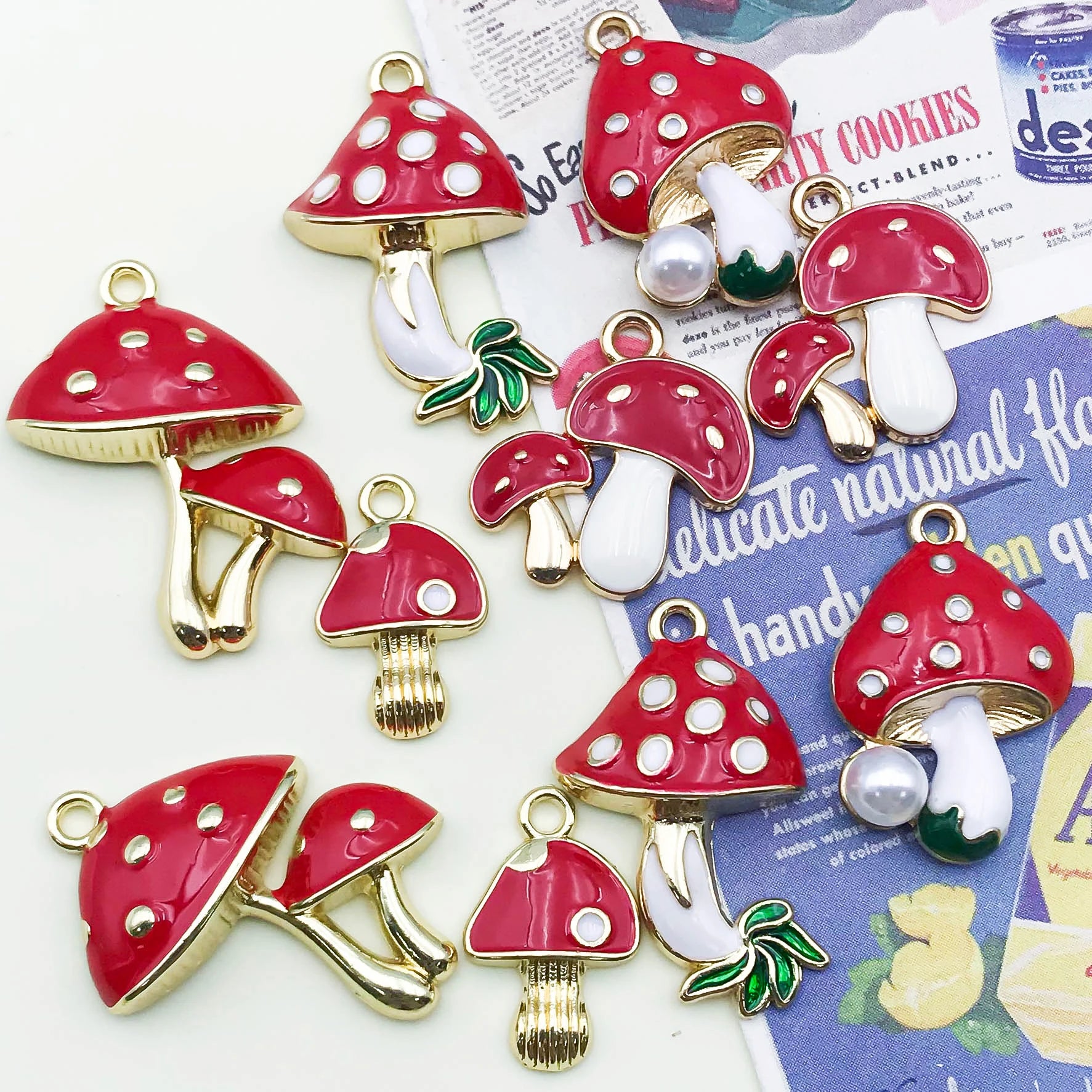 Red and white mushroom-shaped charms with gold accents on a newspaper background