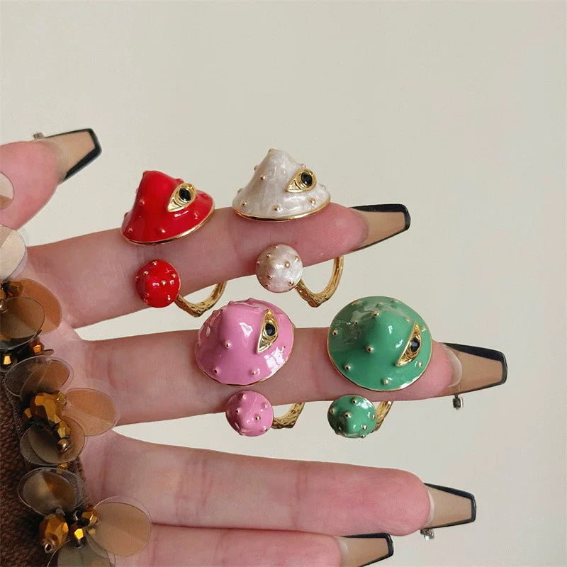 Hand wearing multiple colorful rings on a plain background